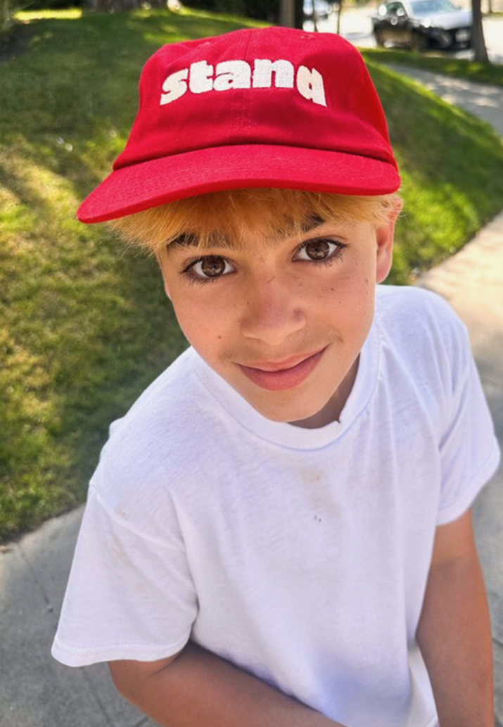 Stand kid in a red Stand cap on a sidewalk
